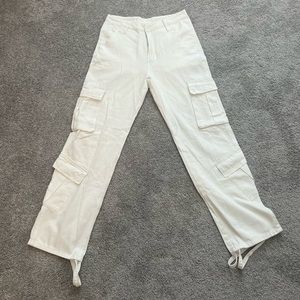 White cargo pants with adjusters at the ankle.